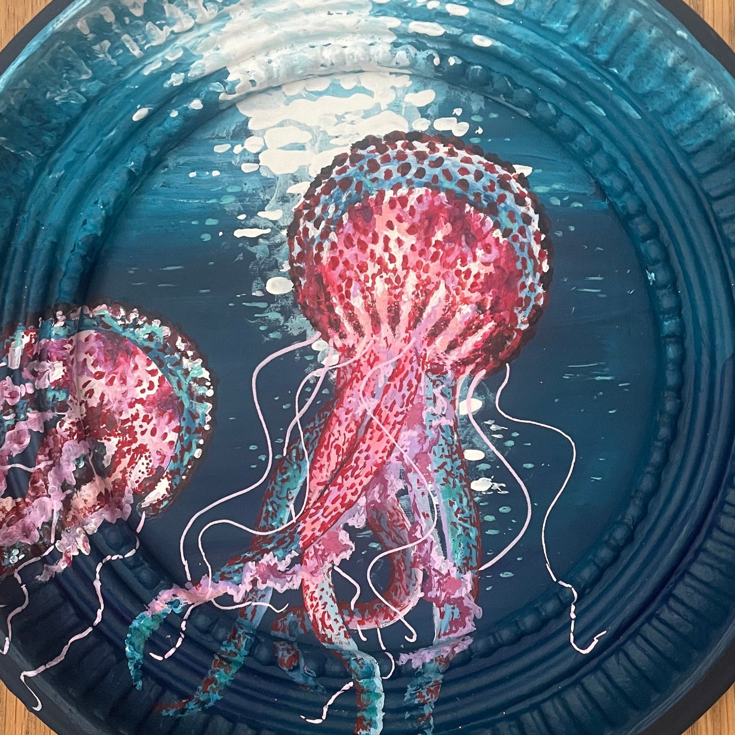 Round blue frame with pink jellyfish design.