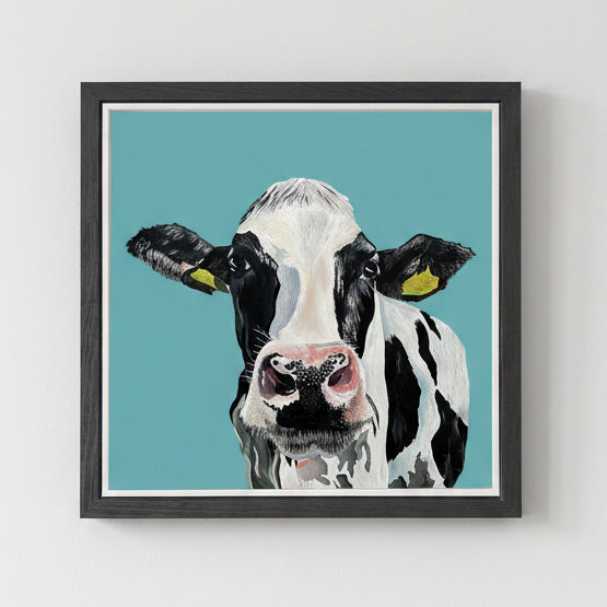 Framed artwork of a cow's face on a teal background