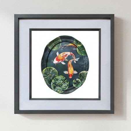Framed wall art featuring a painted koi fish pond scene with two orange-and-white koi fish among green lily pads on a dark water background.