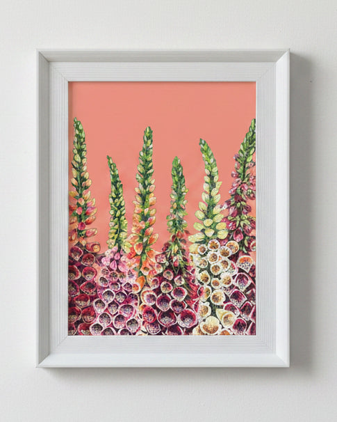 A framed art print featuring a stylized painting of tall green and pink flowers against a solid coral background, housed in a white frame.