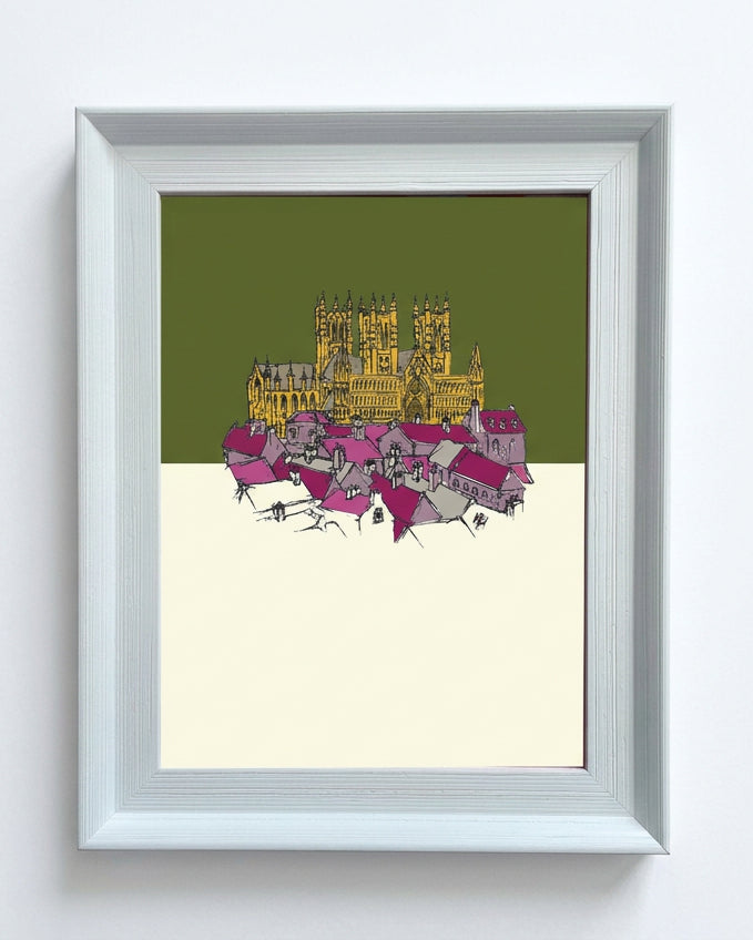A framed art print featuring a stylized illustration of Lincoln cathedral and city. The print has an olive green top half, an off-white bottom half, and a yellow/gold architectural illustration in the center.